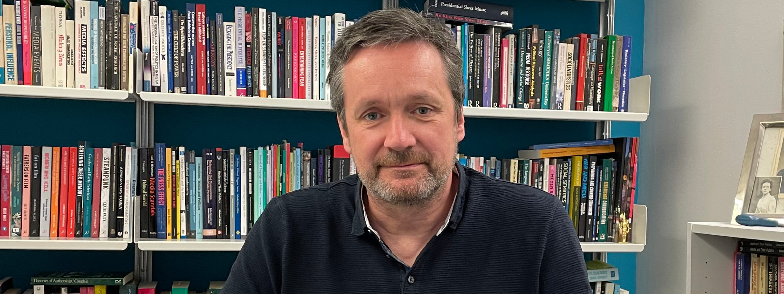 A man sitting in front of a bookshelf