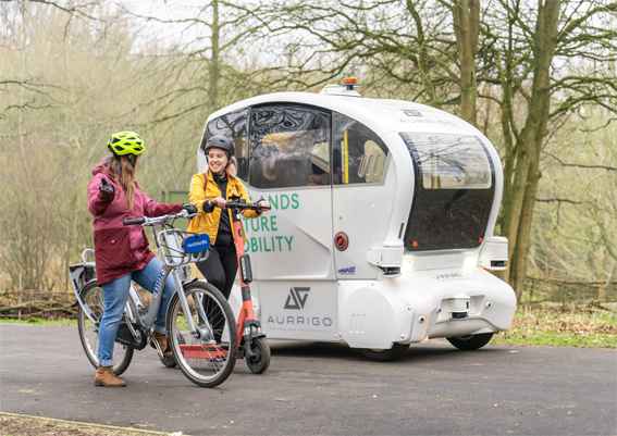 Two cyclists alongside a futuristic vehicle Two cyclists alongside a futuristic vehicle