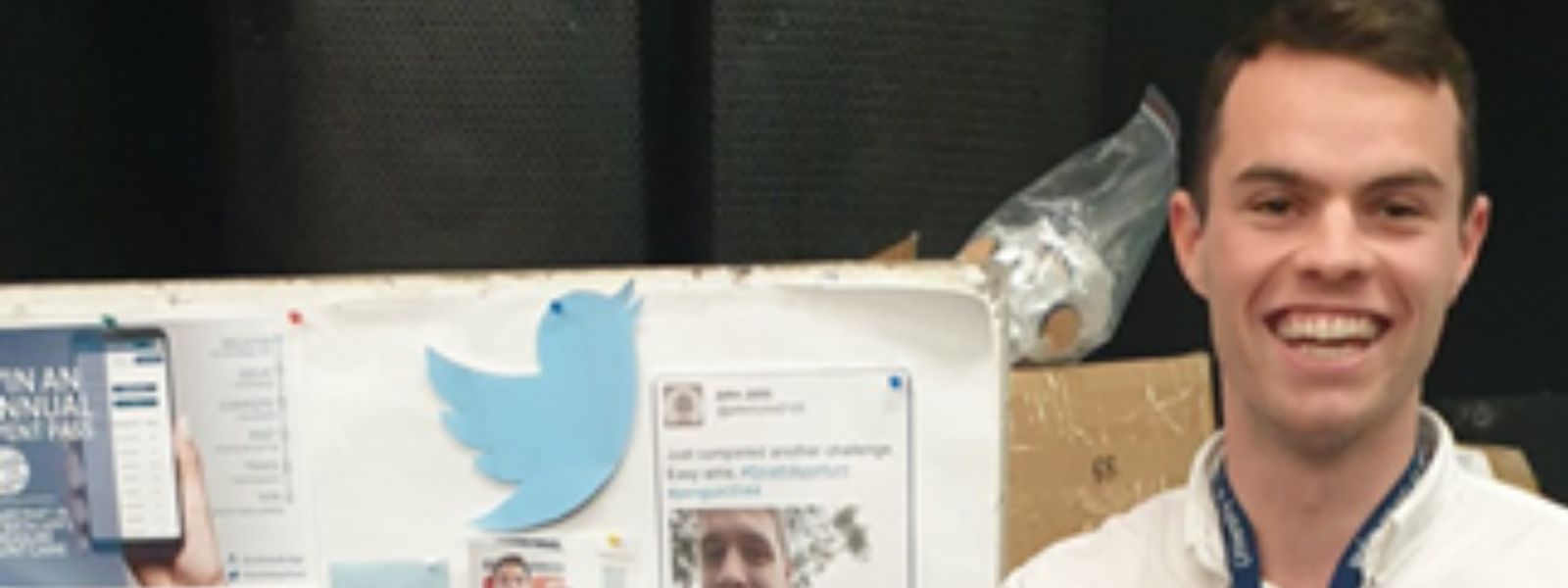 A student at Freshers Fair in front of a board of tweets and Twitter logos