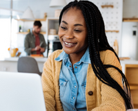 a student sitting at a desk smiling at a laptop