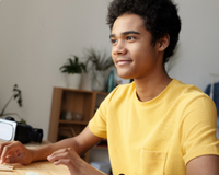 A  student sitting at a desk wearing a yellow tshirt